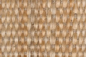 Textura de fibras naturales tejidas en patrón entrecruzado, con tonos beige y marrón claro. Superficie uniforme y repetitiva que evoca un material artesanal, rústico y orgánico, vista en primer plano.